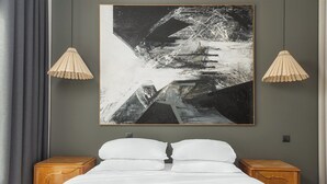 A bedroom with a bed, two nightstands, a large abstract painting, and two pendant lights. - Anvy Stylish Suites Ioannina (Ioannina)