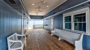 A covered wooden deck with white benches and a large window.