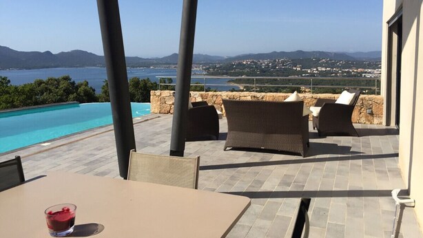 Eine Terrasse mit Pool, Gartenmöbeln und Blick auf das Meer und die Berge.