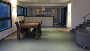 Eine moderne Küche mit Essbereich, großen Fenstern und einer Treppe.