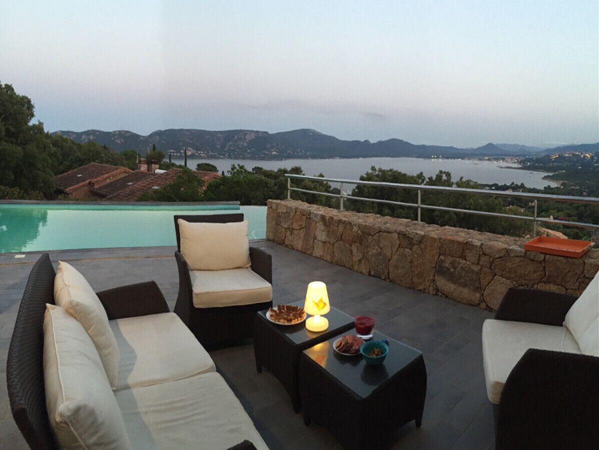 An outdoor seating area with a pool, stone wall, and a view of the landscape.