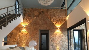 Ein modernes Interieur mit Steinwand, einer Treppe und Blick durch eine Glastür.