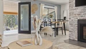 A modern living room with a fireplace, a dining area, and a large window with a view of greenery. - Beautiful Nature Retreat minutes to Mt. Rainier (Elbe)