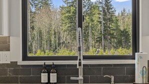A kitchen with a large window overlooking a forest, a faucet, and two bottles of dish soap. - Beautiful Nature Retreat minutes to Mt. Rainier (Elbe)