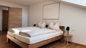A modern bedroom with a wooden bed, a small stool, and a ceiling light.