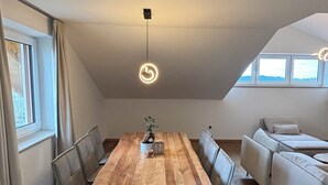 A modern loft with a wooden dining table, grey upholstered chairs, and a sofa.