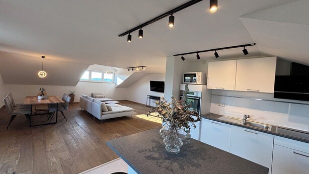 A modern loft apartment with a dining area, living space, and kitchen.