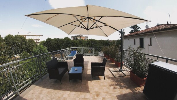 Une terrasse sur le toit, dotée d’un grand parasol, de mobilier d’extérieur et de plantes en pot.