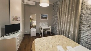 Une chambre à coucher comprenant un lit, un bureau, une chaise, un téléviseur et un appareil de climatisation.