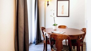 A round wooden dining table with four chairs, a floor lamp, a framed picture on the wall, and a potted plant on the table. - Cosy, Air-conditioned Flat -1br/4p- Geneva (Geneva)