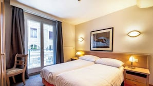 A hotel room with a large bed, two bedside lamps, a chair, a nightstand, and a window with curtains. - Cosy, Air-conditioned Flat -1br/4p- Geneva (Geneva)
