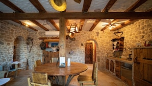 A rustic stone kitchen with wooden furniture, a round table, and a wooden ceiling. - Holiday Home Leptir (Siveric)