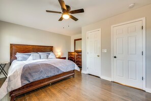 A bedroom with a wooden bed, a ceiling fan, and white doors. - 11 Mi to Mercedes-benz Stadium: Home w/ Yard! (Conley)