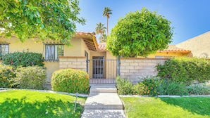 A residential house with a concrete pathway leading to the front door, surrounded by well-maintained lawns and various shrubs. - Palm Desert Condo w/ Community Perks: WFH Friendly (Palm Desert)