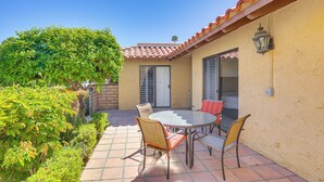 A patio with a round table and chairs, a door, and a small tree. - Palm Desert Condo w/ Community Perks: WFH Friendly (Palm Desert)