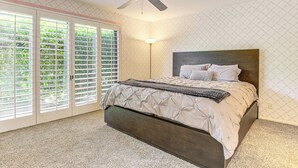 A bedroom with a bed, a ceiling fan, a floor lamp, and a sliding glass door leading to a balcony. - Palm Desert Condo w/ Community Perks: WFH Friendly (Palm Desert)