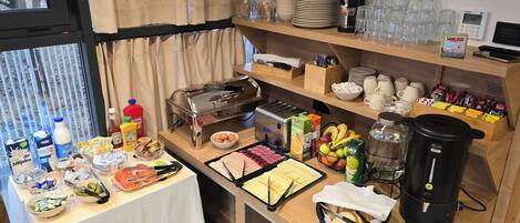 A breakfast buffet setup with various food items, a coffee machine, and a digital clock.