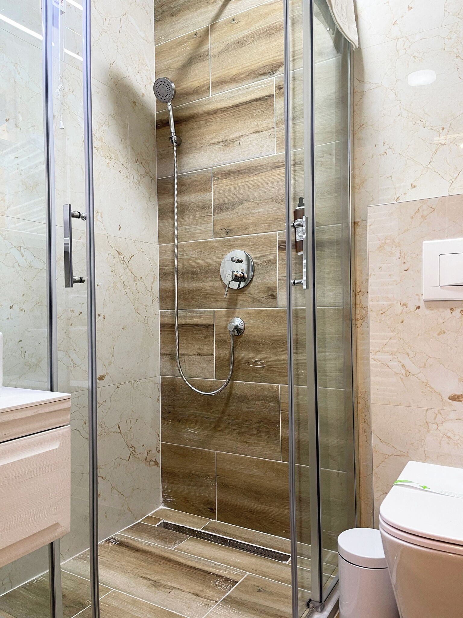 Une salle de bain moderne avec une douche à parois de verre, des carreaux de marbre et des toilettes.