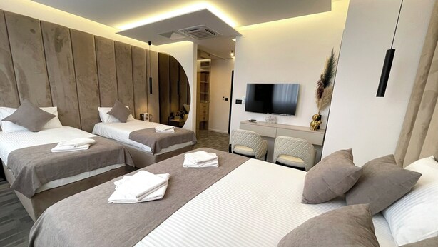 Une chambre d’hôtel moderne équipée de deux lits, d’une télévision et d’un bureau.