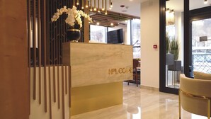 Un comptoir d’accueil avec une enseigne indiquant « NPL COVE », un vase rempli de fleurs blanches et un aménagement intérieur moderne avec une cloison en verre et une vue sur l’extérieur.