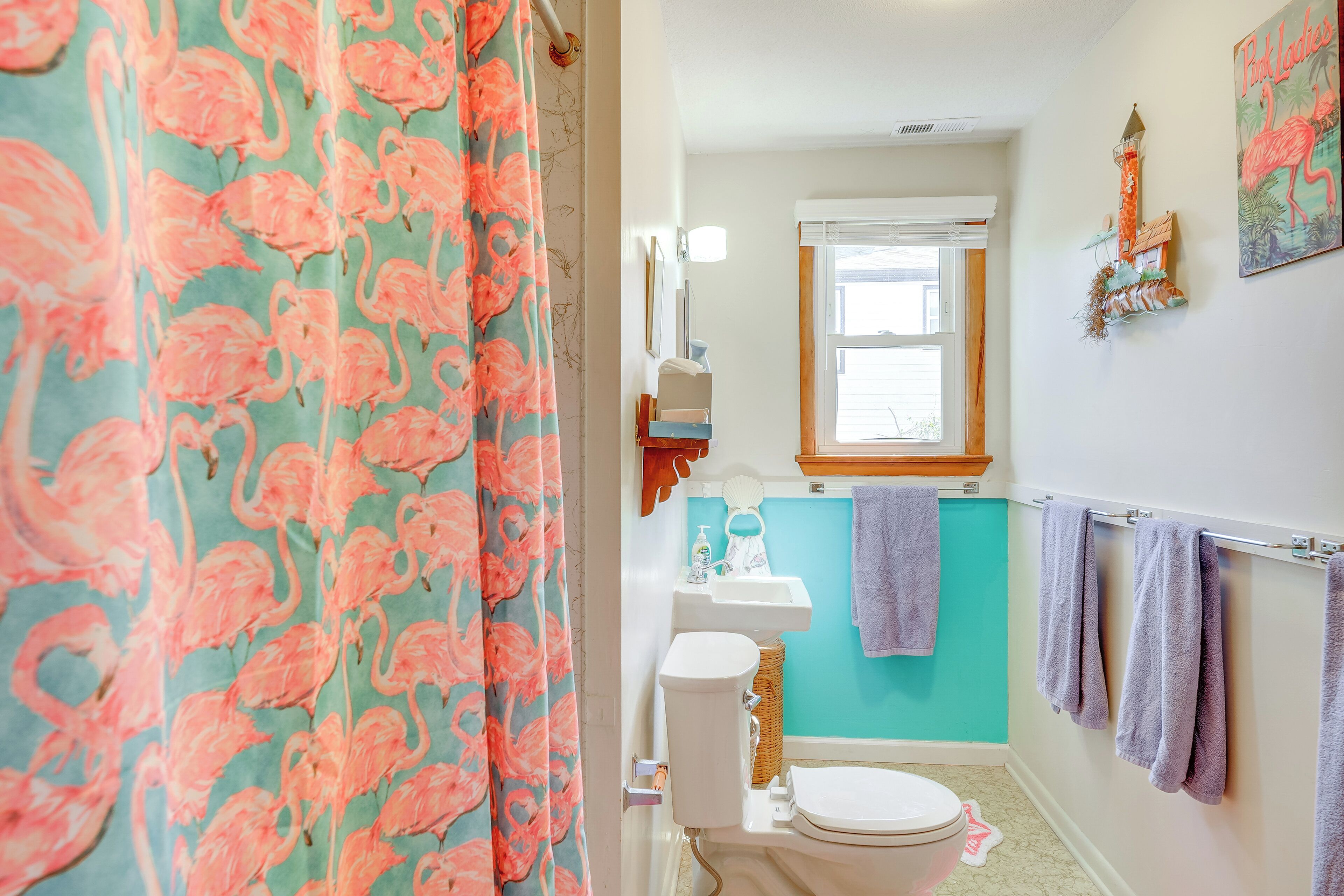 A bathroom with a toilet, sink, and a window.