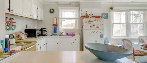 A kitchen with white cabinets, a stainless steel stove, and a large blue bowl on the counter.