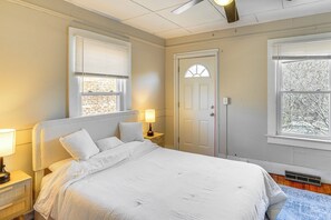 Un dormitorio con cama, lámparas de noche, una puerta y ventanas.
