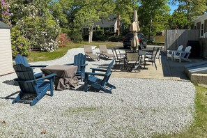 Ein Sitzbereich im Freien mit Adirondack-Stühlen und einem Tisch, umgeben von einer Kiesfläche.