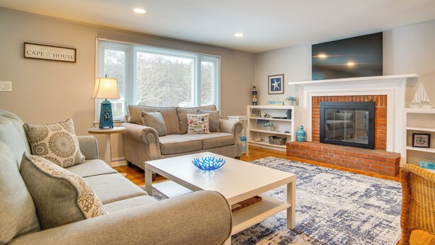 A living room with a sofa set, a coffee table, a fireplace, and a television mounted on the wall. - < 1 Mi to Craigville Beach: Home w/ Patio & BBQ (Centerville)