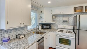 A kitchen with white cabinets, a granite countertop, a microwave, a stove, and a refrigerator. - < 1 Mi to Craigville Beach: Home w/ Patio & BBQ (Centerville)