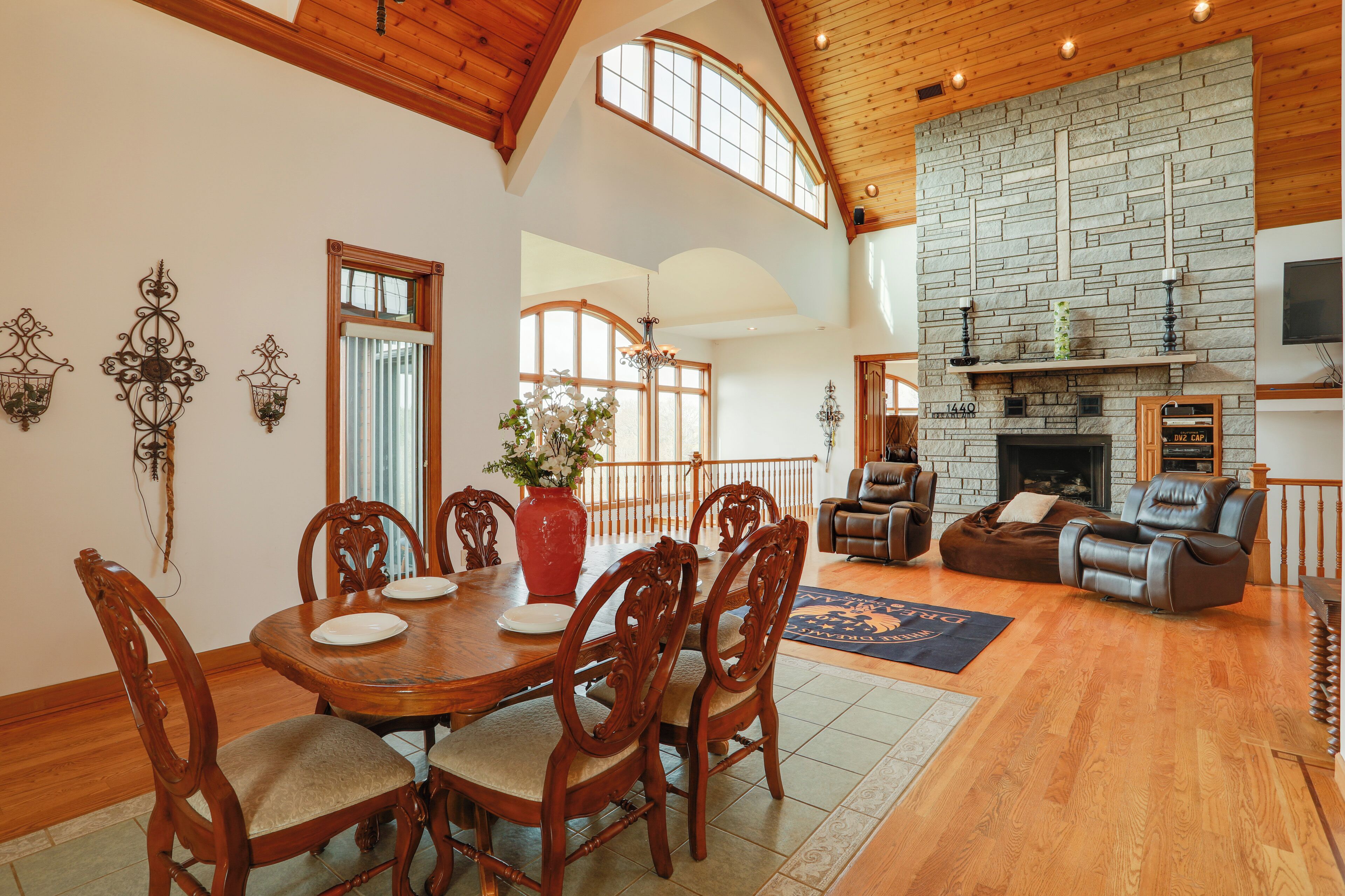 A spacious living room with a stone fireplace, wooden dining table, and leather seating.