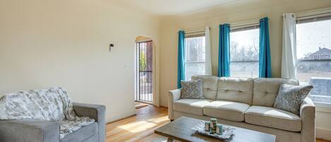 A living room with a grey sofa, a wooden coffee table, and a beige sofa with patterned cushions.