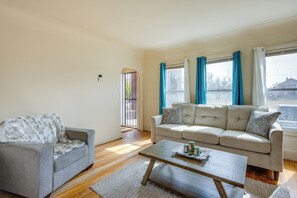 A living room with a grey sofa, a wooden coffee table, and a beige sofa with patterned cushions. - Pet-friendly Detroit Apt: 5 Mi to Motown Museum! (Detroit)