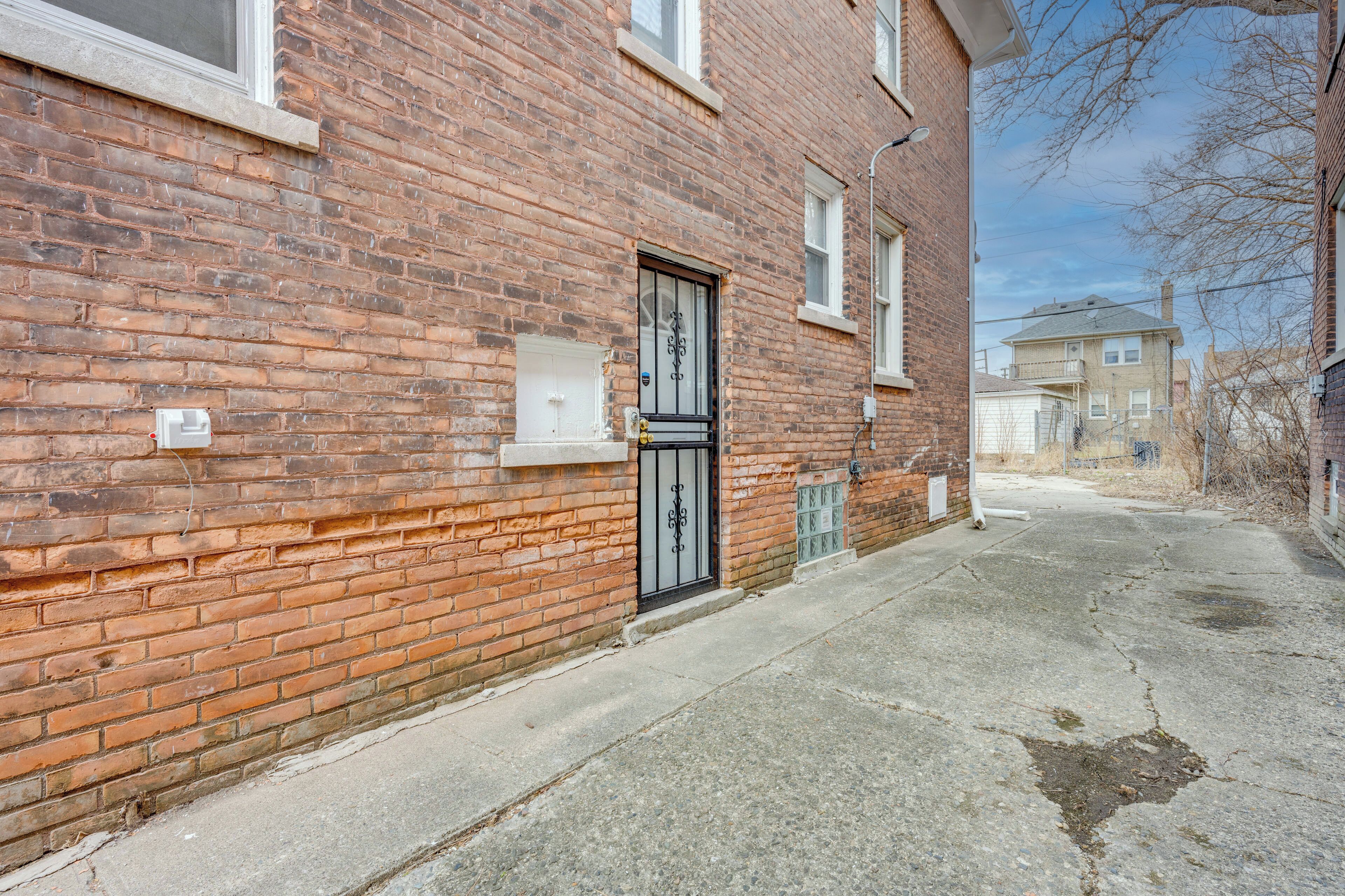 A brick building with a black metal door, a small window, and a visible electrical box.