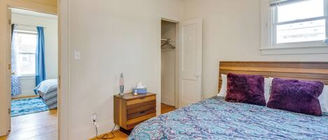 A bedroom with a bed, a dresser, a closet, and a window.