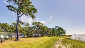 A beachfront property with multiple cabins, a grassy path, and a pier extending into the water. - Relax & Refresh: Waterfront Cottage in Panacea (Panacea)