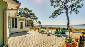 A wooden deck with outdoor seating and potted plants, overlooking a body of water. - Relax & Refresh: Waterfront Cottage in Panacea (Panacea)