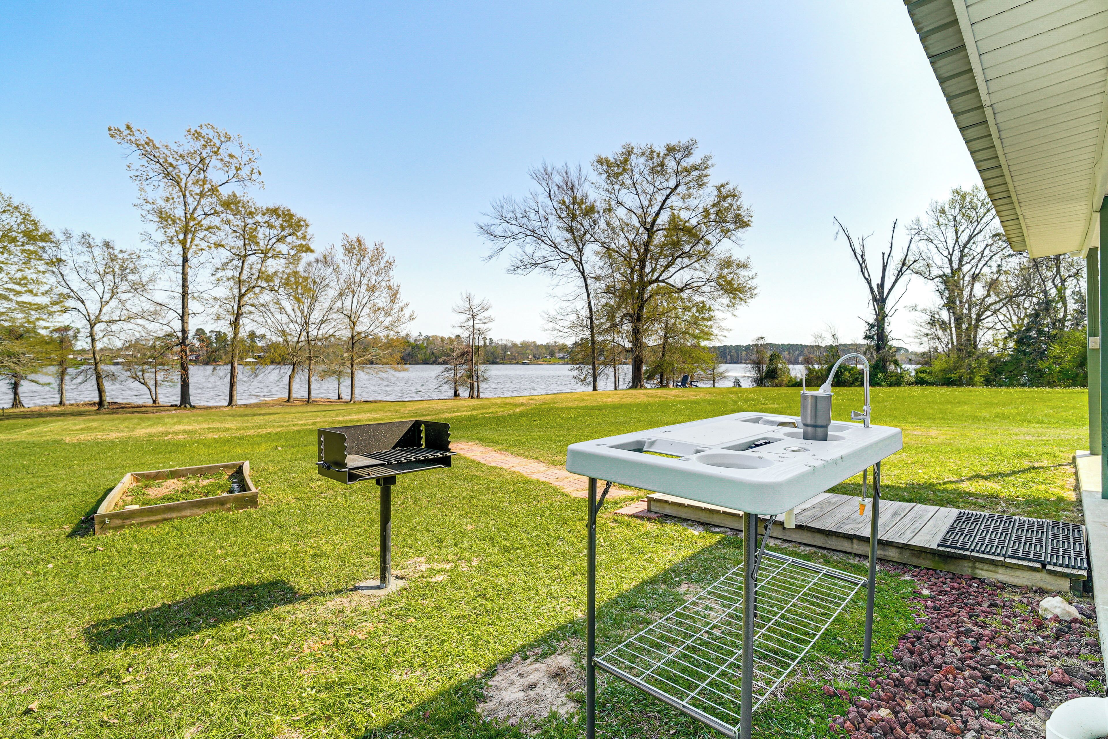 Une terrasse extérieure équipée d’un barbecue, d’un évier et d’un petit espace aménagé avec vue sur un lac.