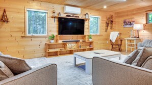 Un intérieur de chalet chaleureux, avec un revêtement mural en bois, un téléviseur à écran plat, un canapé et une table basse.