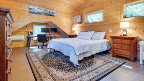 Une chambre confortable avec un lit, un bureau et une commode, dotée de murs en bois et d’une grande fenêtre.