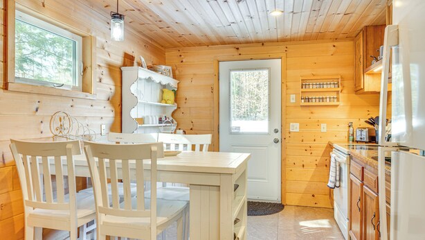 L’intérieur d’une cabane en bois comprend une table à manger, des chaises, un coin cuisine avec des placards et une porte dotée d’une fenêtre.