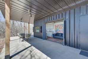 A covered outdoor area with a dining table and chairs, a sofa, and a colorful abstract painting. - Swim, Boat & Fish: Waterloo Retreat w/ Views! (Waterloo)