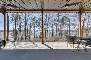A covered patio with a table and chairs, overlooking a forested area and a body of water. - Swim, Boat & Fish: Waterloo Retreat w/ Views! (Waterloo)