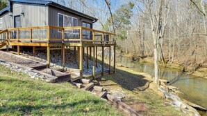 Une cabane dotée d’une terrasse donnant sur une rivière, entourée d’arbres.