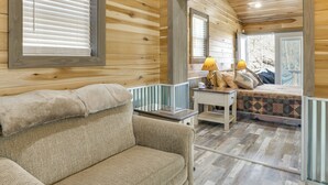 Une chambre confortable dans un chalet en rondins, avec un lit, un canapé et une petite table sur laquelle se trouve une lampe.