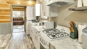 Une cuisine moderne avec des meubles blancs, une cuisinière à gaz, un four à micro-ondes et un évier.