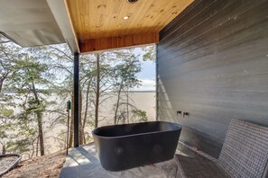 A bathtub in a room with a view of trees and water. - (Waterloo)
