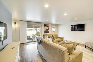 Una sala moderna con un sofá, sillones, un televisor y un comedor con mesa y sillas.