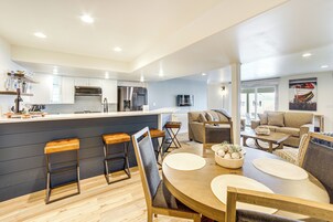 Una cocina moderna con una isla central, taburetes de bar y un comedor con una mesa redonda y sillas.