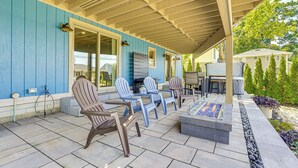 Eine überdachte Terrasse mit Sitzgelegenheiten im Freien, einem Grill und einem Kamin aus Stein.